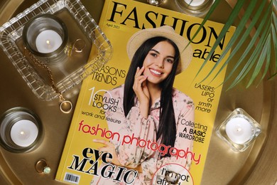 Fashion magazine, jewelry and candles on table, flat lay