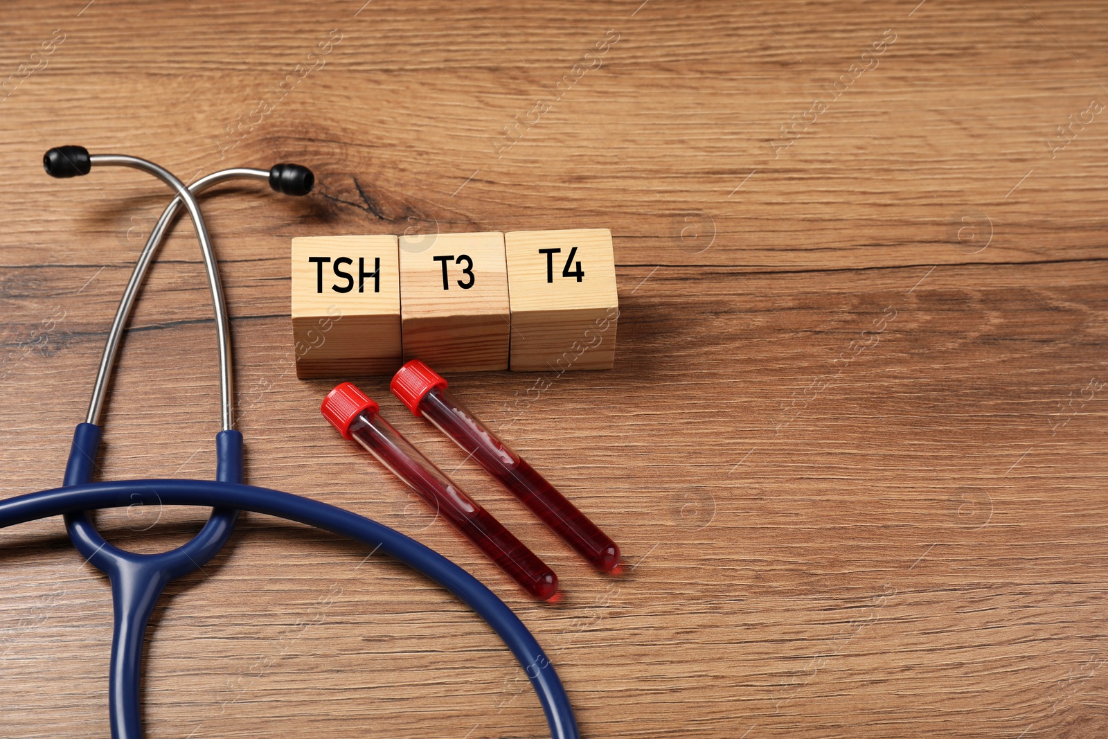 Photo of Endocrinology. Stethoscope, cubes with thyroid hormones and blood samples in test tubes on wooden table. Space for text