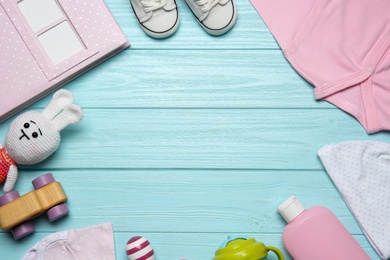 Frame of baby clothes and accessories on light blue wooden background, flat lay. Space for text