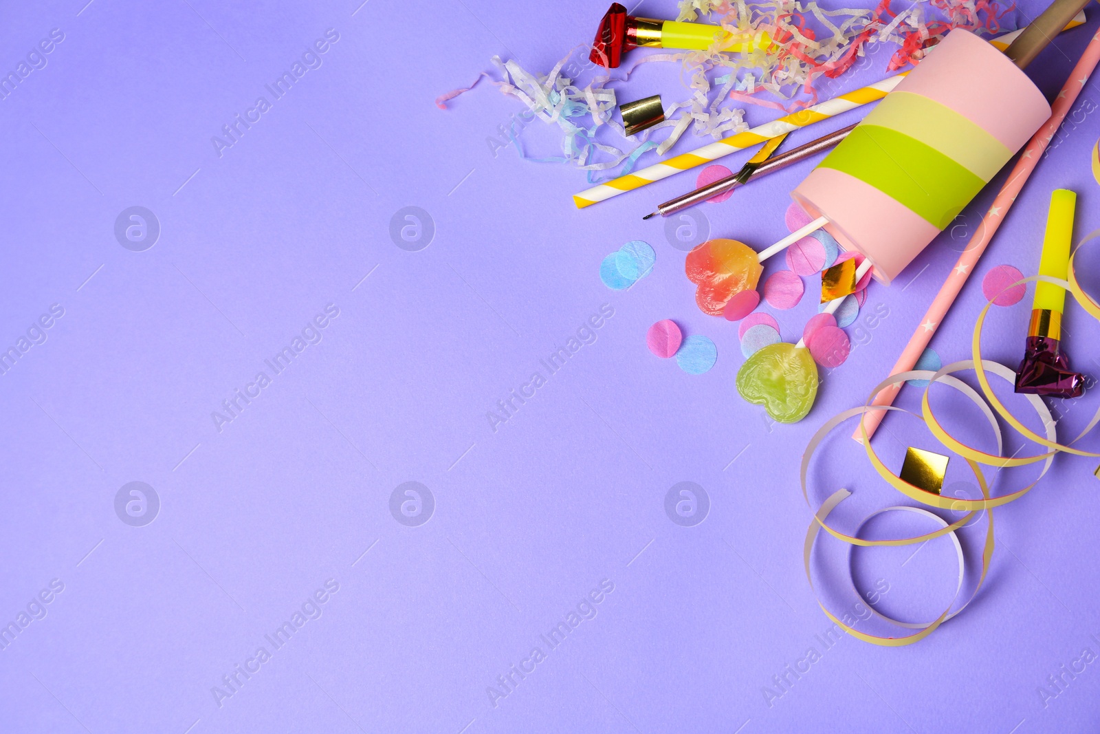 Photo of Party popper, lollipops and festive decor on violet background, flat lay