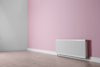 Photo of Modern radiator on color wall indoors. Central heating system