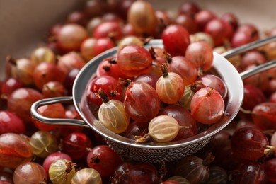 Photo of Bowl with sieve full of ripe gooseberries, closeup