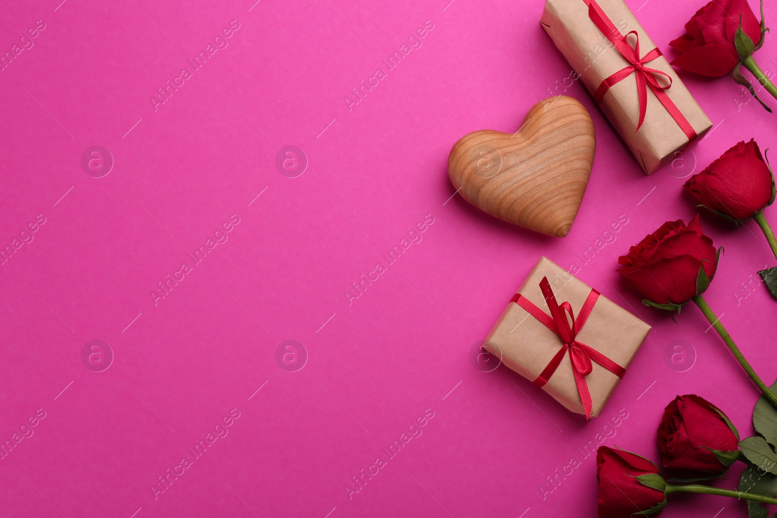 Photo of Beautiful gift boxes, roses and toy heart on pink background, flat lay with space for text. Valentine's day celebration