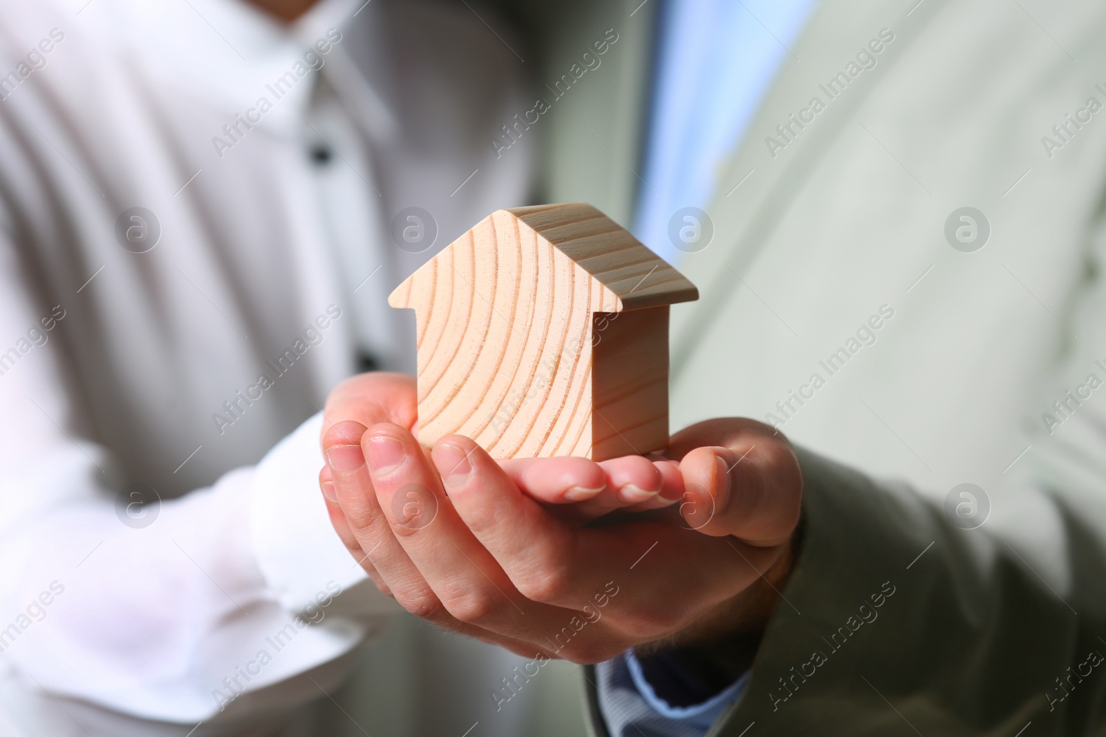 Photo of Young couple holding house figure, closeup. Home insurance