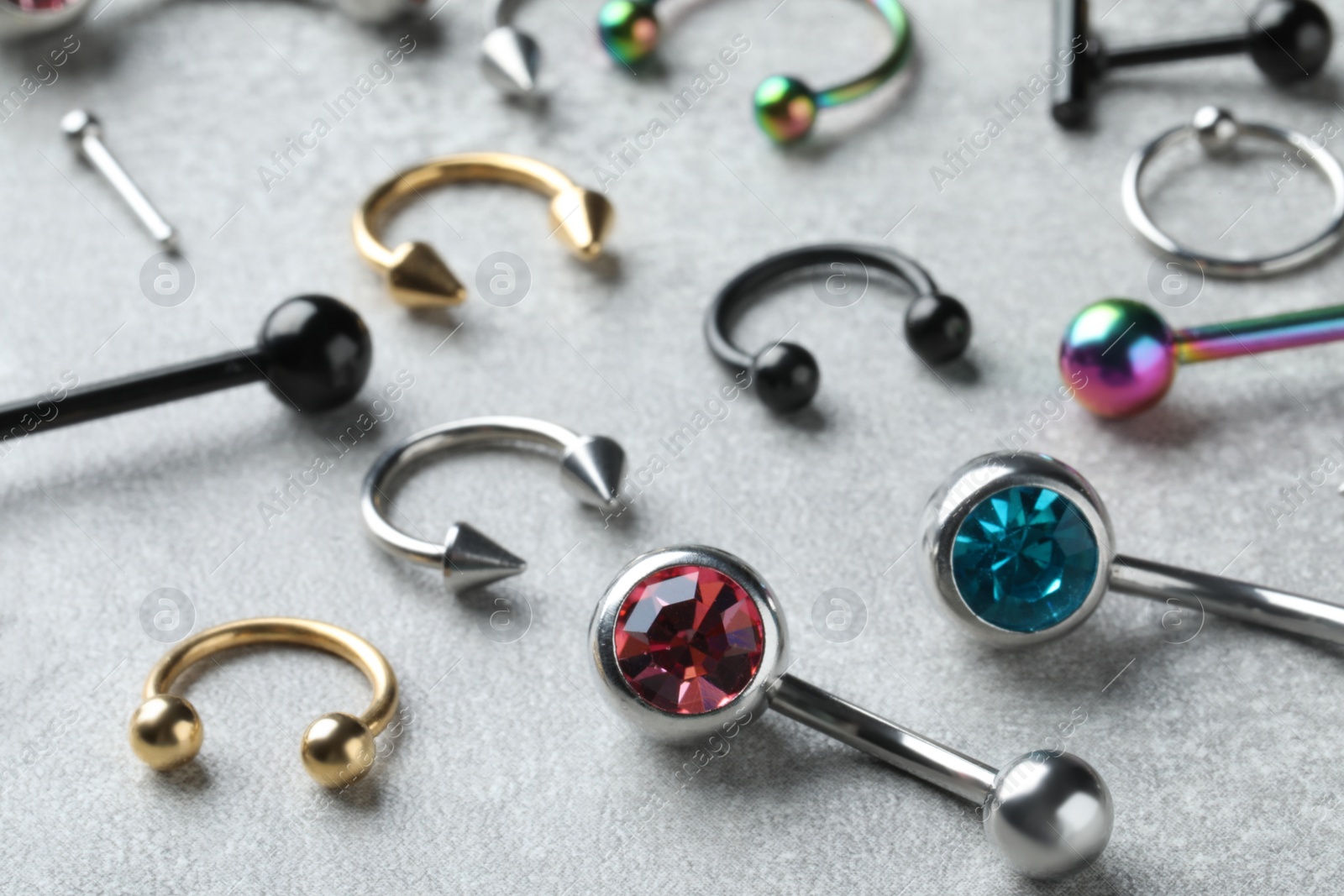 Photo of Stylish piercing jewelry on light grey table, closeup