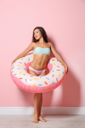 Beautiful young woman with inflatable ring near color wall