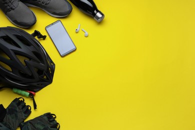 Photo of Flat lay composition with different cycling accessories on yellow background, space for text
