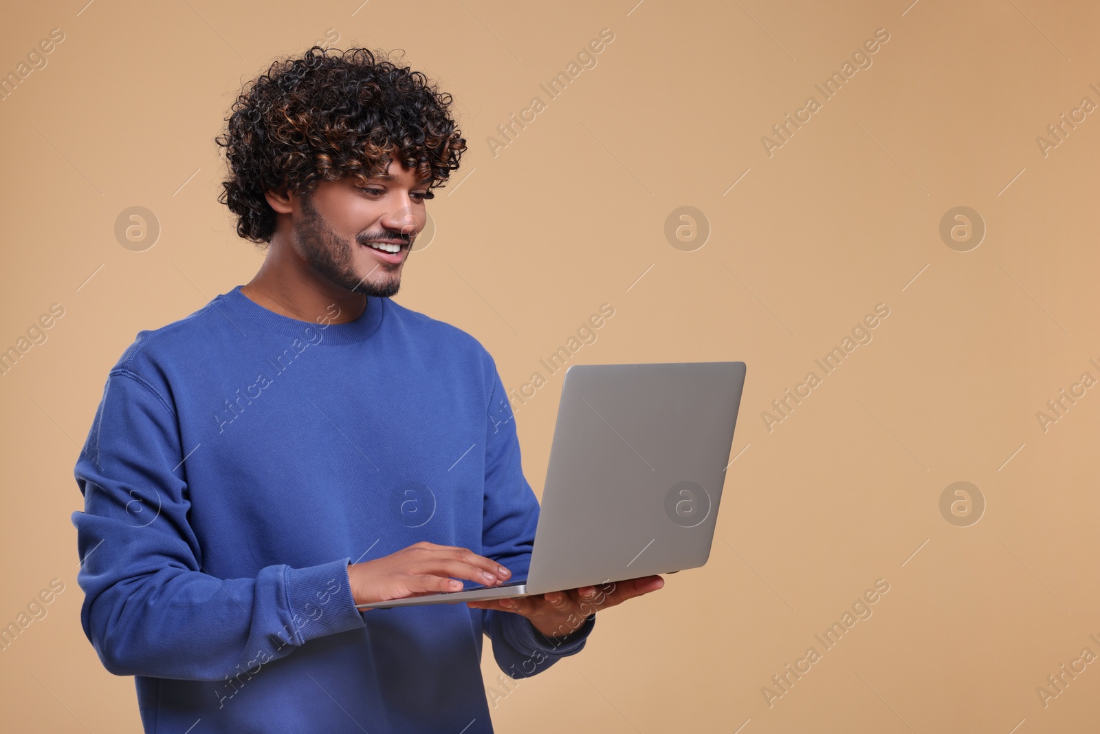 Photo of Smiling man with laptop on beige background. Space for text