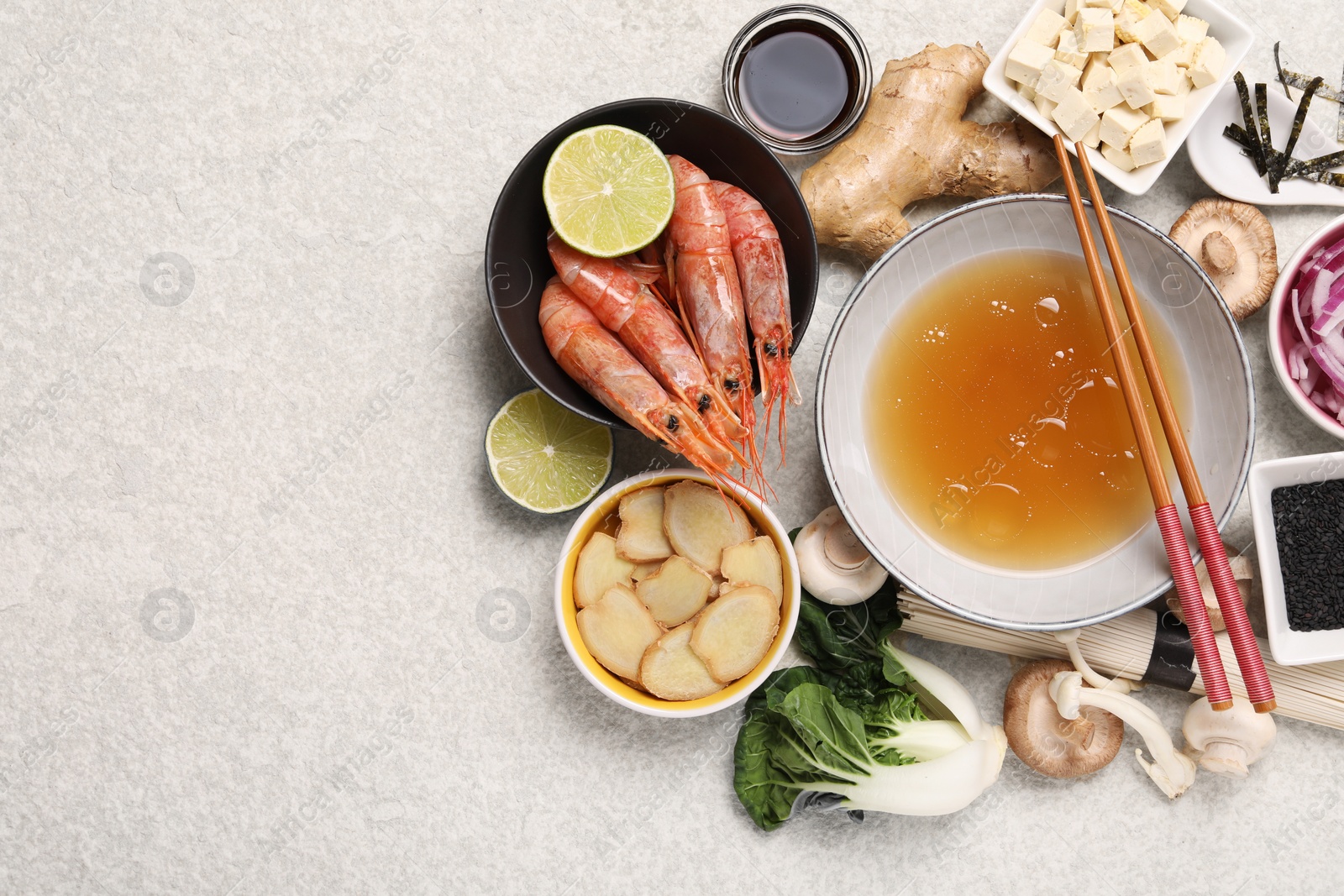 Photo of Cooking delicious ramen soup. Different ingredients and chopsticks on beige table, flat lay. Space for text