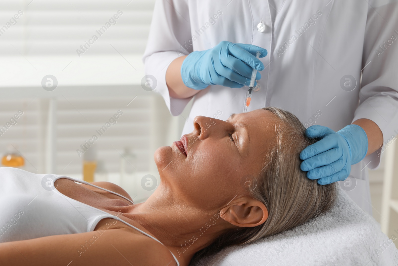 Photo of Doctor giving facial injection to senior woman in clinic. Cosmetic surgery