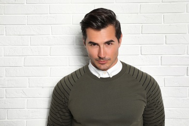 Portrait of handsome young man on white brick wall