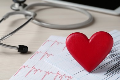 Red heart with cardiogram and stethoscope on white wooden table, closeup. Cardiology concept