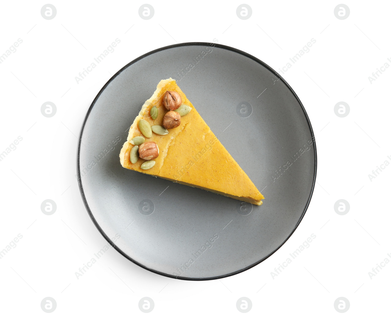 Photo of Piece of delicious pumpkin pie with hazelnuts and seeds isolated on white, top view
