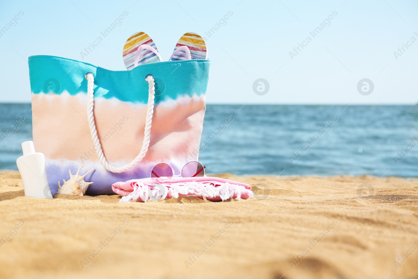 Photo of Stylish beach accessories on sand near sea. Space for text