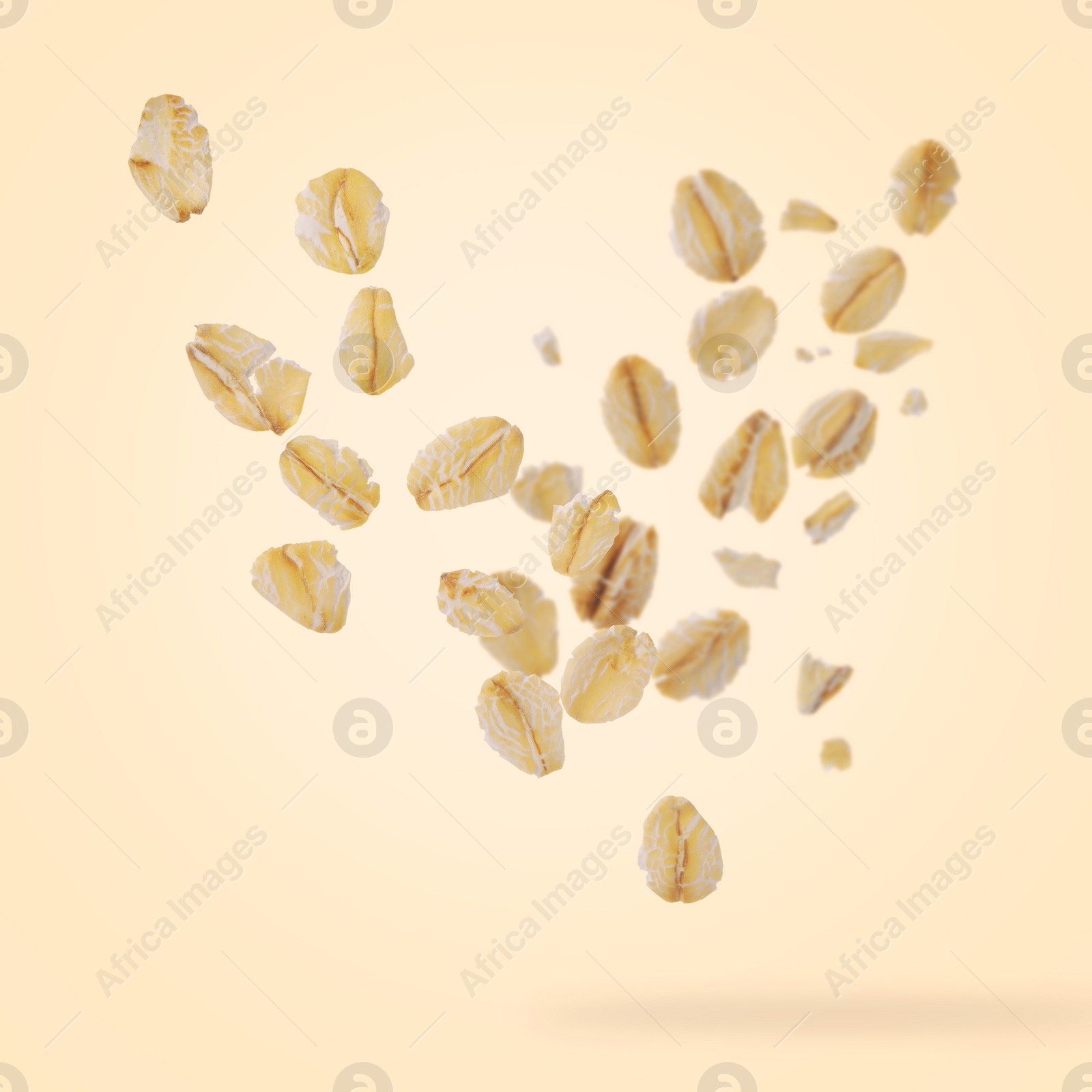 Image of Rolled oat flakes falling on beige background