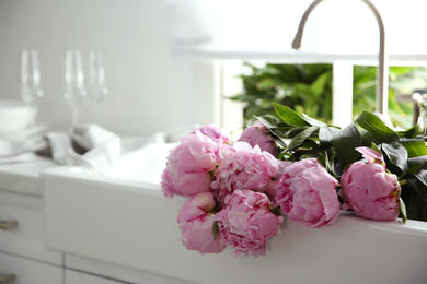 Bouquet of beautiful pink peonies in kitchen sink