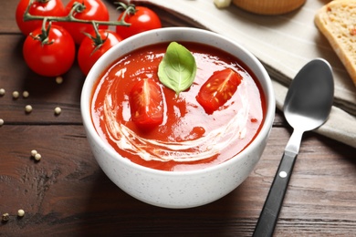 Photo of Bowl with fresh homemade tomato soup on wooden table