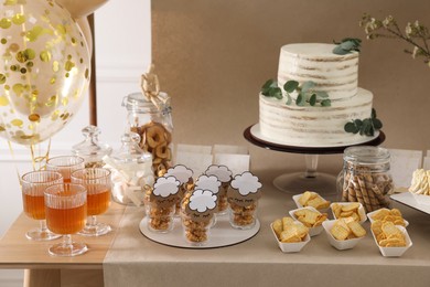 Photo of Beautiful cake and other treats on table in room. Baby shower party