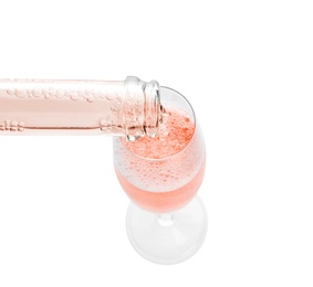 Photo of Pouring rose champagne from bottle into glass on white background