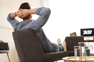 Young man relaxing in comfortable chair at workplace