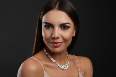 Photo of Beautiful young woman with elegant jewelry on dark background