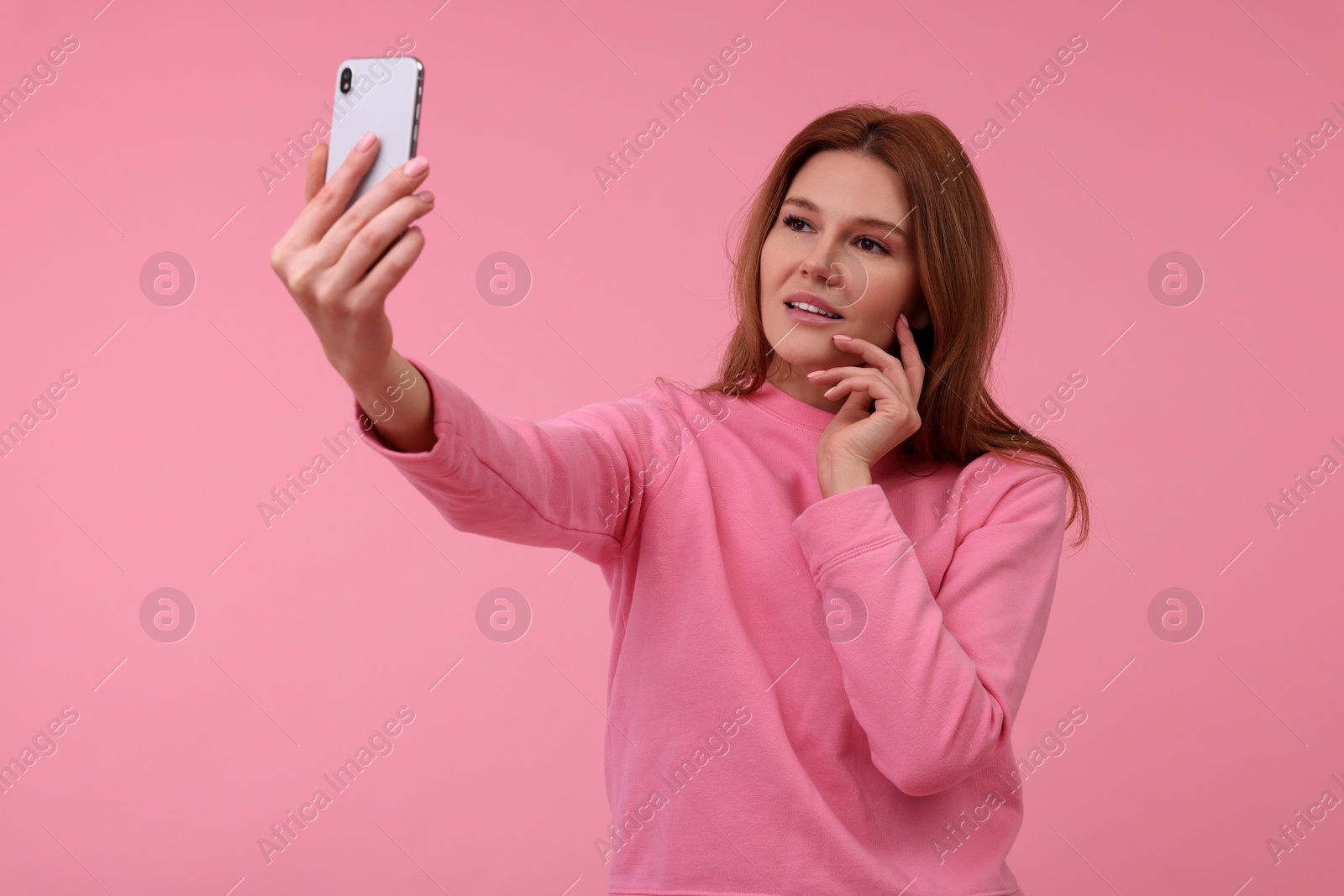 Photo of Beautiful woman taking selfie on pink background