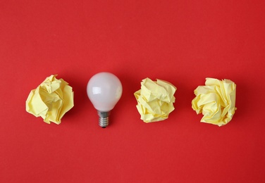 Photo of Flat lay composition with lamp bulb and crumpled paper on color background