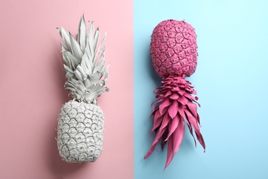 White and pink pineapples on color background, flat lay. Creative concept