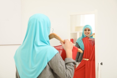 Photo of Muslim woman choosing clothes in modern shop