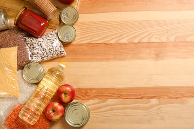 Photo of Many different products and space for text on wooden background, flat lay. Food donation