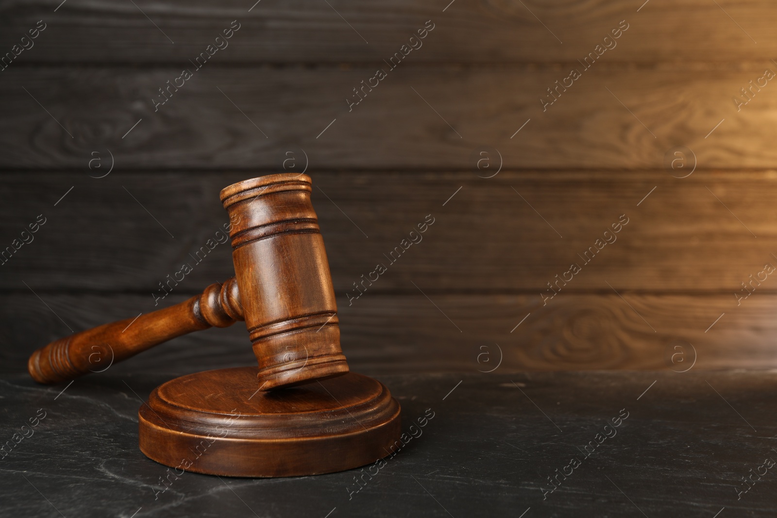 Photo of Wooden gavel on dark textured table. Space for text