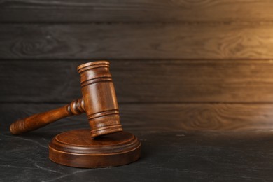 Photo of Wooden gavel on dark textured table. Space for text