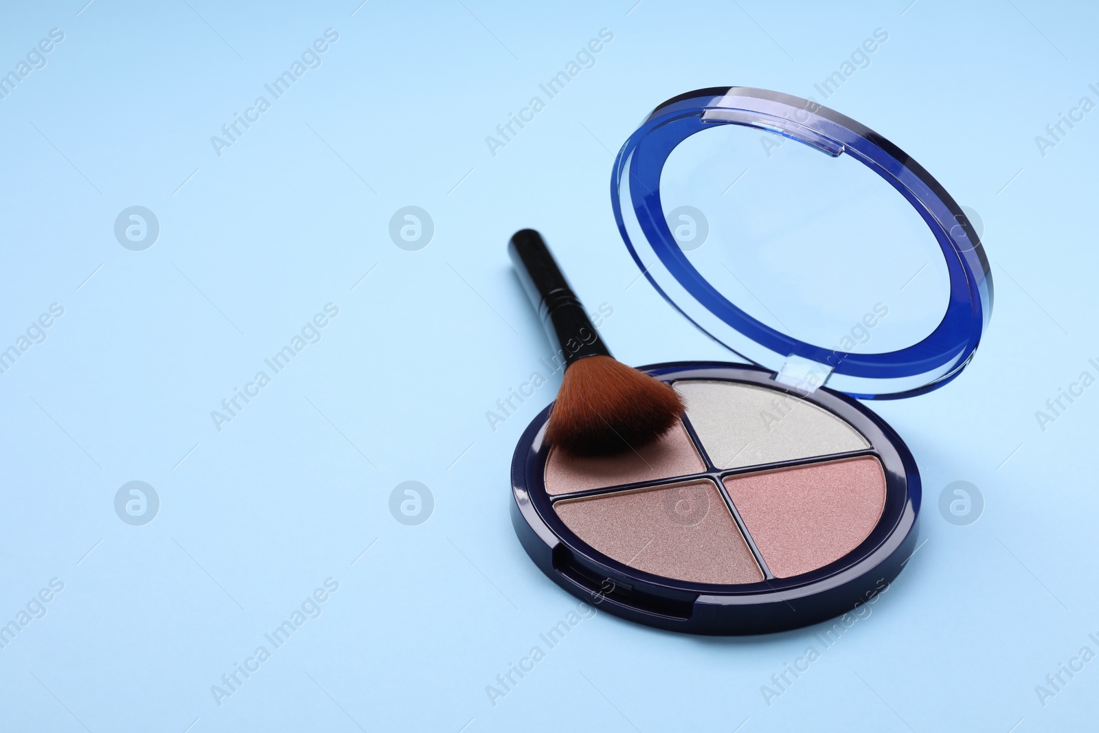 Photo of Contouring palette and brush on light blue background, space for text. Professional cosmetic product