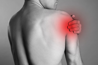 Image of Man suffering from shoulder pain, closeup. Black and white photo 