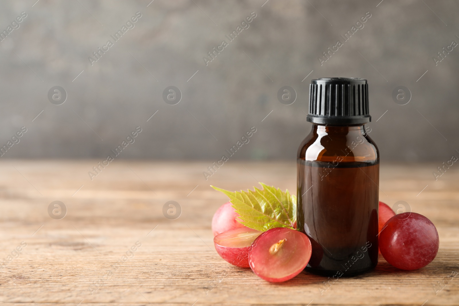 Photo of Bottle with natural grape seed oil on wooden table, space for text. Organic cosmetic