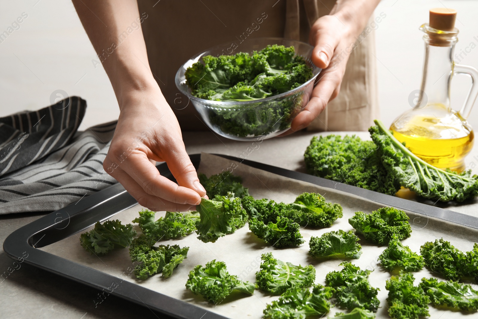 Photo of Woman preparing kale chips at table, closeup