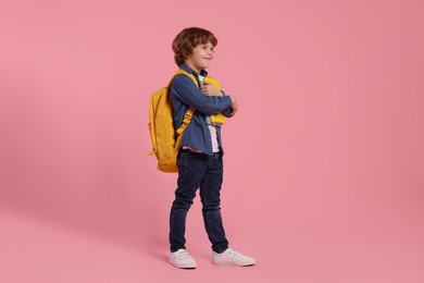 Photo of Happy schoolboy with backpack and books on pink background