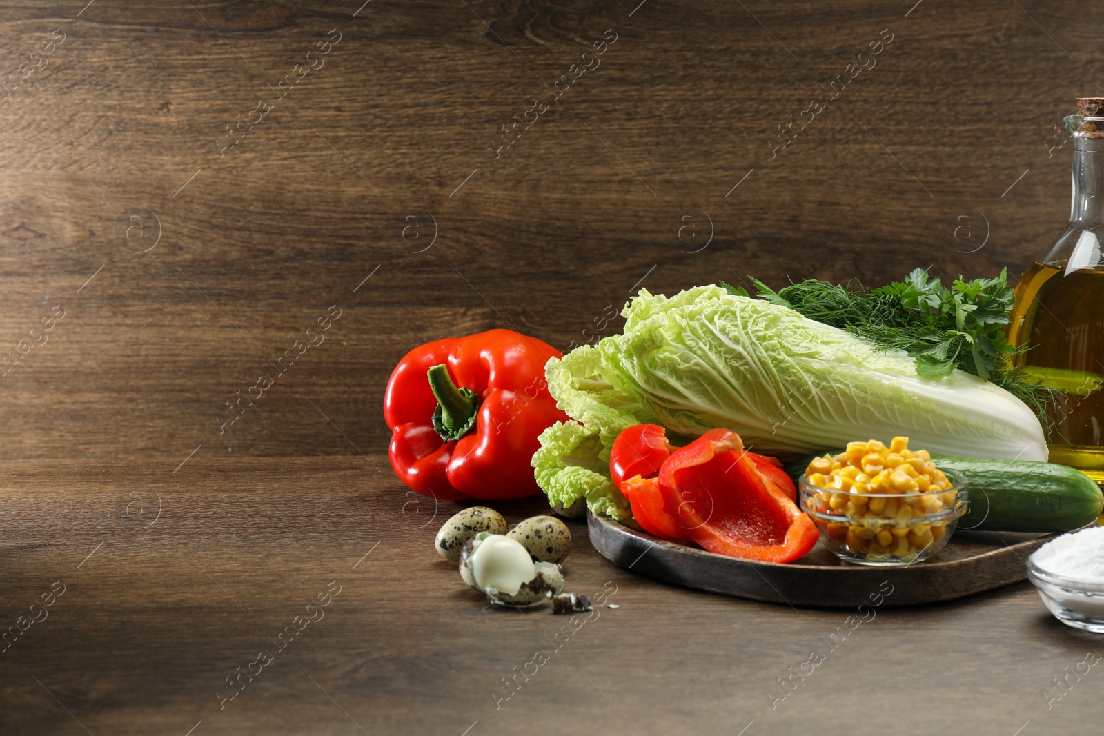 Photo of Chinese cabbage and different products on wooden table, space for text