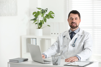 Portrait of male doctor in white coat at workplace