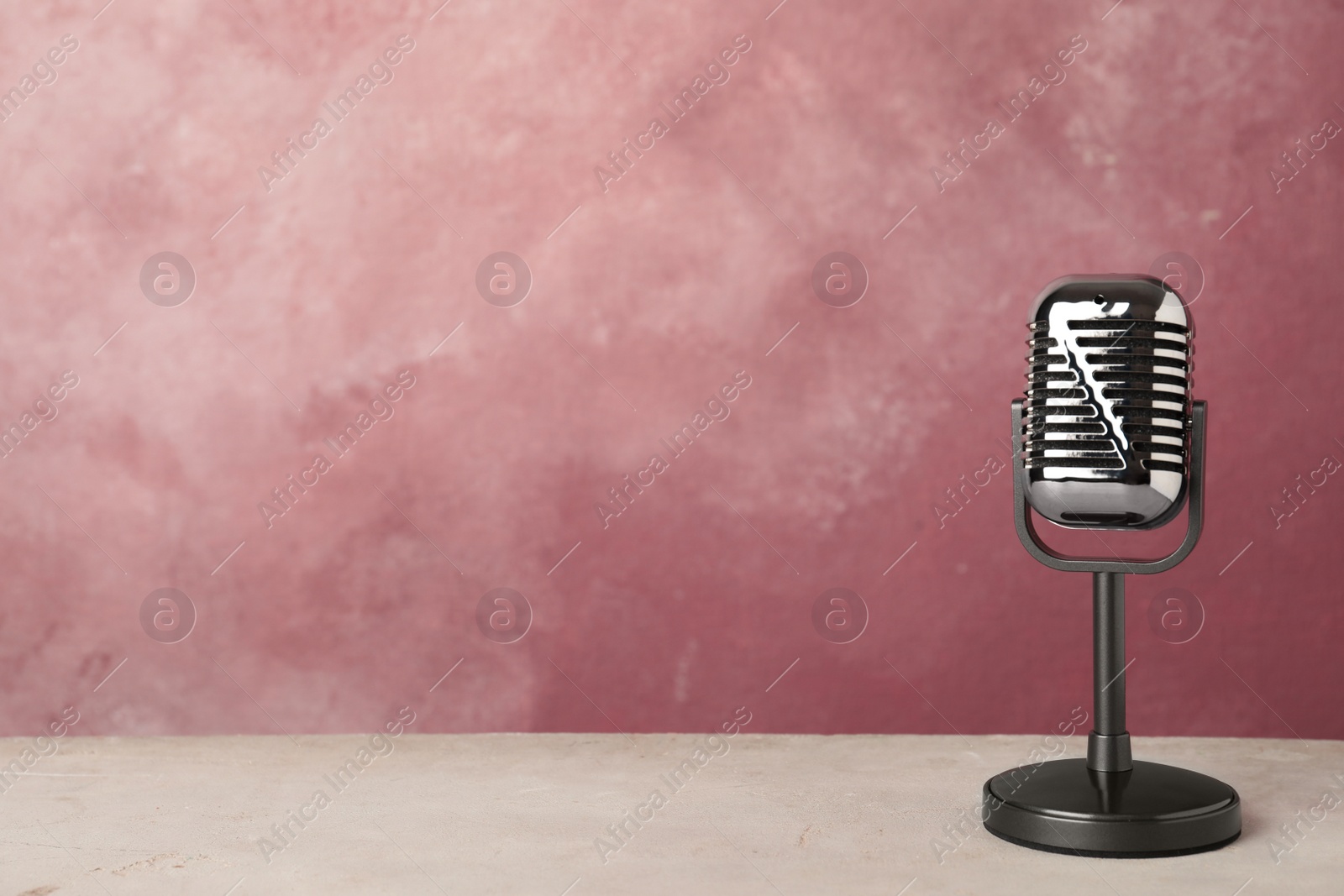 Photo of Retro microphone on table against color background. Space for text