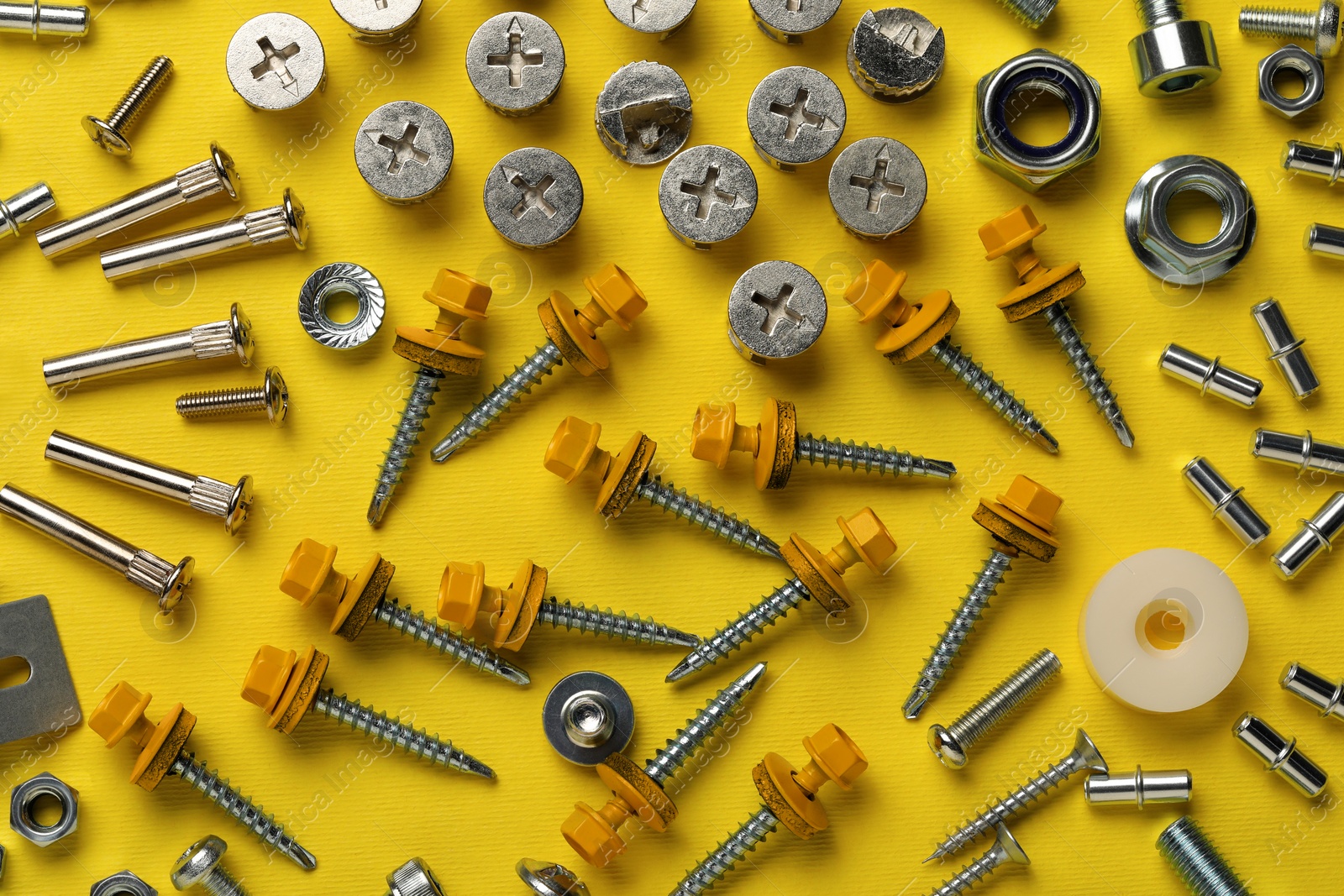 Photo of Many different fasteners on yellow background, flat lay