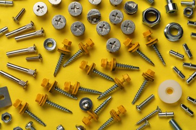 Photo of Many different fasteners on yellow background, flat lay