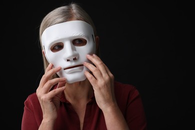 Photo of Multiple personality concept. Woman in mask on black background, space for text