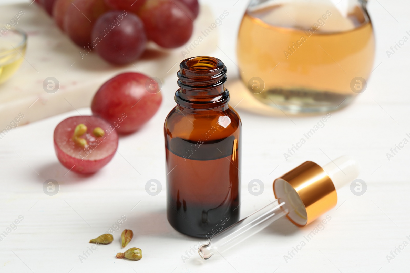 Photo of Natural grape seed oil on white wooden table. Organic cosmetic