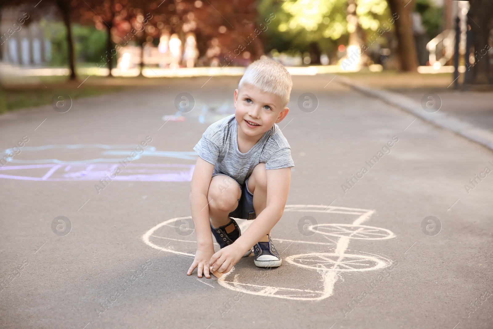 Photo of Little child drawing car with chalk on asphalt