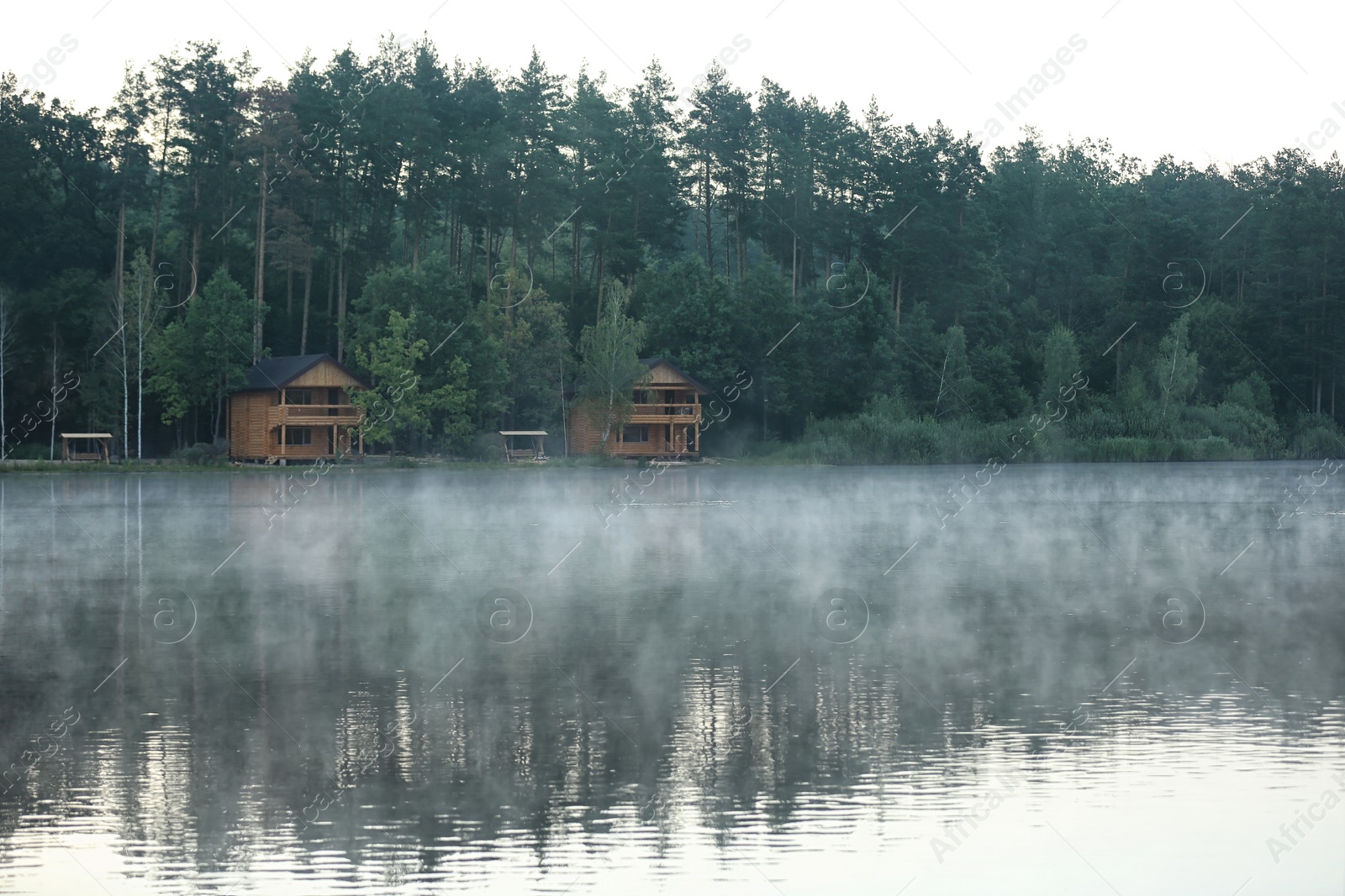 Photo of Beautiful landscape with forest and houses near lake. Camping season