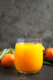 Photo of Glass of fresh tangerine juice and fruits on black table