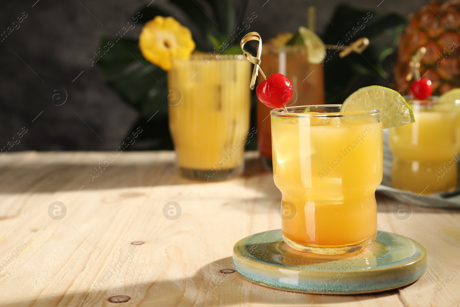 Photo of Tasty pineapple cocktail with cherry and lime on wooden table. Space for text