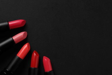 Beautiful lipsticks on black background, flat lay. Space for text