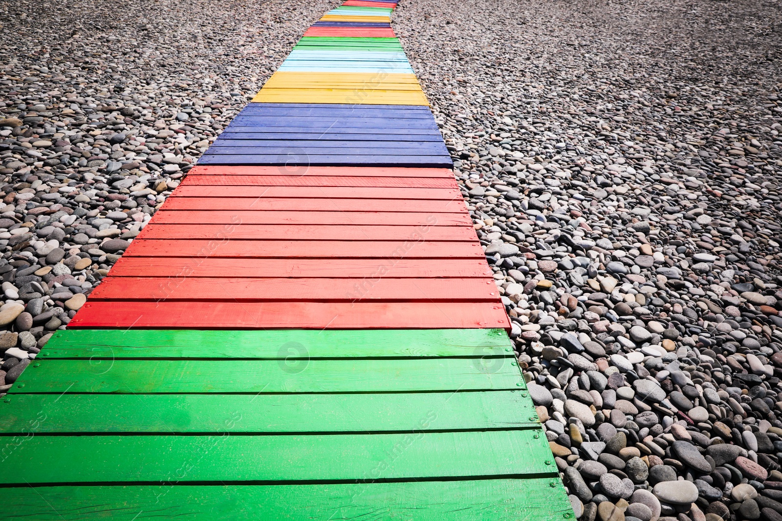 Photo of Colorful wooden walkway on stony beach, closeup
